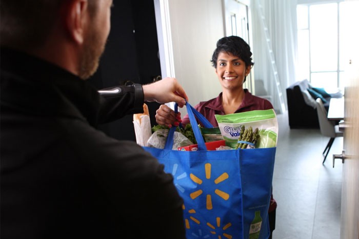A happy customer accepts her grocery delivery. Une cliente satisfaite accepte sa livraison d'épicerie.